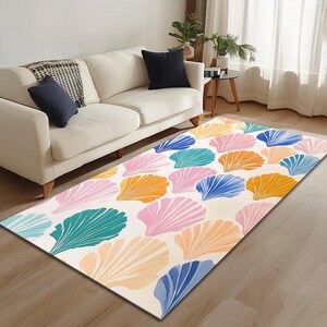 May include: A white area rug with a colorful seashell pattern. The rug features pink, blue, green, and orange seashells on a white background.