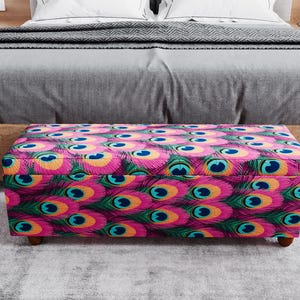 A colorful ottoman with a pattern of peacock feathers is placed in front of a bed, creating a vibrant and eye-catching display.