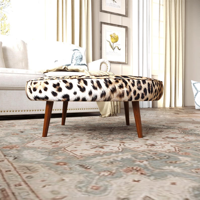 a leopard print ottoman with a wooden base, placed on a patterned rug in a living room setting.