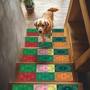 May include: A golden retriever descends a wooden staircase decorated with patterned stair treads. The treads display a paisley design in shades of red, green, pink, and orange. A potted plant is visible in the background. The stairs are made of wood.