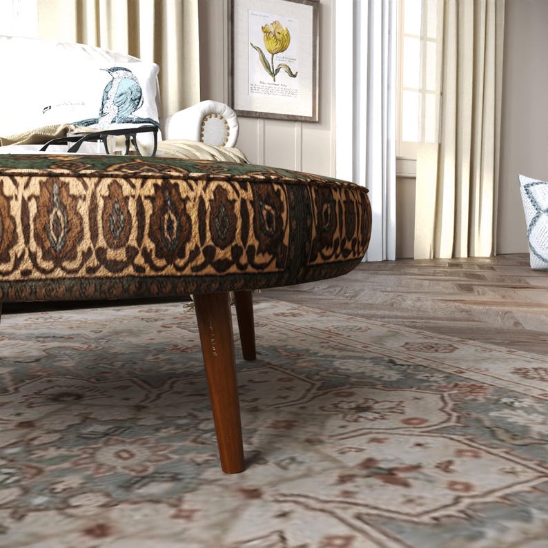 a cozy living room with a round ottoman, a patterned rug, and a framed picture on the wall.
