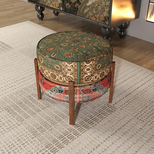 a round, colorful ottoman with a patterned design, placed on a rug in a room with a bookshelf in the background.