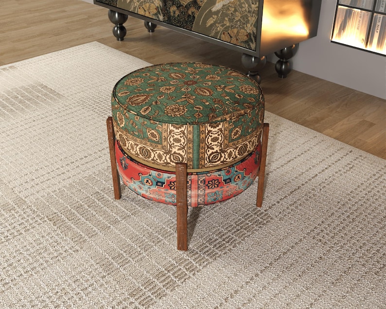 a round, colorful ottoman with a patterned design, placed on a rug in a room with a bookshelf in the background.