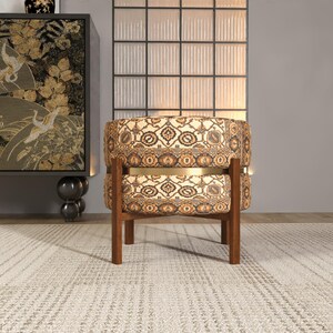 a modern, circular chair with a floral patterned upholstery, placed on a white rug in a minimalist setting.