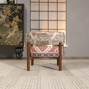 a colorful, patterned chair with a wooden frame, placed in front of a large window with a black and white patterned curtain.