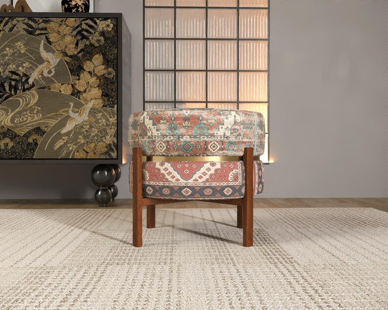 a colorful, patterned chair with a wooden frame, placed in front of a large window with a black and white patterned curtain.