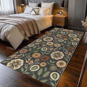 May include: A rectangular floral rug with a dark gray background. The rug features a repeating pattern of stylized flowers in shades of brown, beige, and green, with green leaves and stems. The rug is placed on a dark wood floor.