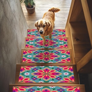 Può includere: Un golden retriever scende una scala di legno adornata con gradini colorati. I gradini presentano uno sfondo turchese con un motivo floreale rosa, arancione, viola e bianco. Una pianta in vaso è visibile in cima alle scale.