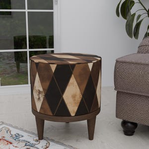 May include: A brown and black patterned ottoman with a round top and four wooden legs. The ottoman is sitting on a white floor with a rug in the foreground.
