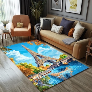Puede incluir: Una alfombra azul y blanca con una ilustración colorida de la Torre Eiffel en París, Francia. La alfombra presenta un puente, un río y árboles en el fondo.