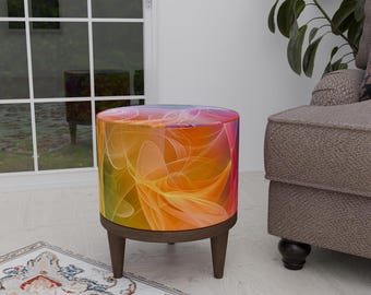 Puede incluir: Un otomano redondo y colorido con un diseño abstracto en espiral en tonos naranja, amarillo, rosa y morado. El otomano tiene cuatro patas de madera.