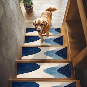 Può includere: Un set di quattro pedate antiscivolo per scale con un motivo astratto di onde blu e bianche. Le pedate sono mostrate su una scala di legno con un cane in piedi sul gradino superiore.
