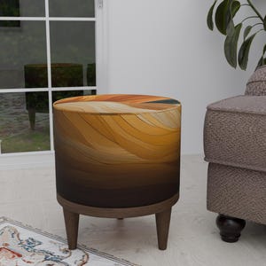 May include: A round, brown and gold patterned ottoman with wooden legs. The ottoman is sitting on a white floor with a rug in the foreground.