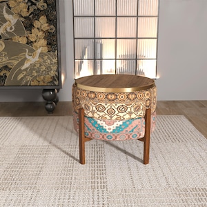 a decorative table with a wooden top, placed on a white rug in a room with a large window and a black and gold tapestry hanging on the wall.