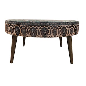 a round table with a patterned seat and four wooden legs.