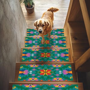 May include: A golden retriever walks down a wooden staircase adorned with teal stair treads. The treads feature a floral pattern with red, yellow, pink, and white flowers. The stairs are in a well-lit home.