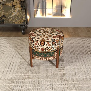a round, colorful ottoman with a patterned design, placed on a beige rug in a room with a fireplace and a bookshelf.