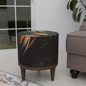 Puede incluir: Un puf redondo negro y marrón con un diseño de tela con temática espacial. La tela presenta un estampado de galaxia con estrellas, planetas y un cometa.