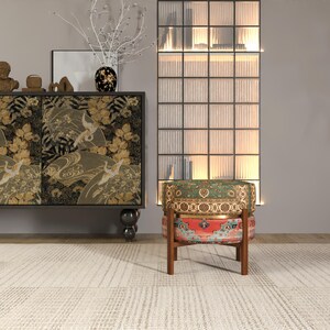 a modern living room with a black and gold cabinet, a colorful patterned chair, and a glass-paneled wall with a decorative plant.