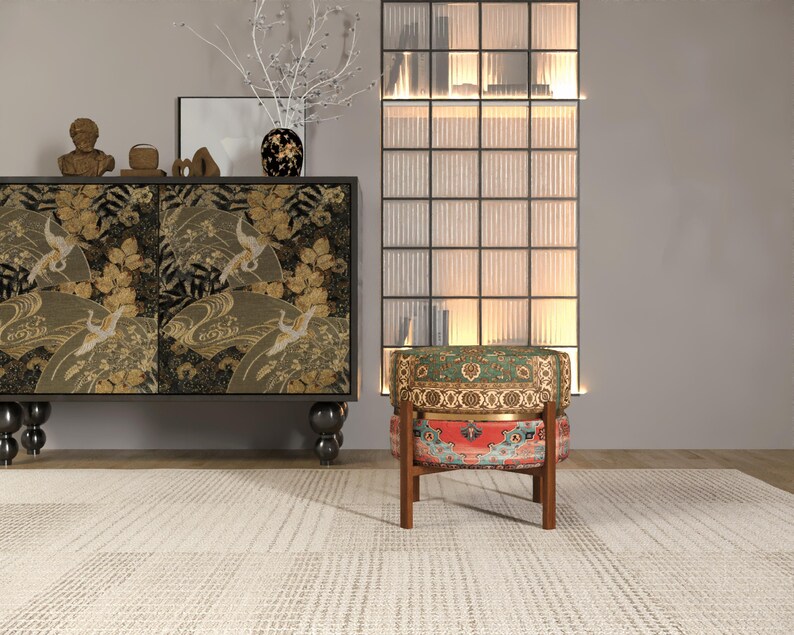 a modern living room with a black and gold cabinet, a colorful patterned chair, and a glass-paneled wall with a decorative plant.