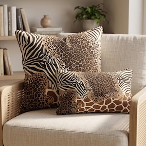 May include: Two decorative throw pillows featuring a patchwork design of animal prints including zebra stripes, leopard spots, and giraffe patterns in shades of brown, black, and cream. The square pillow is positioned behind a smaller rectangular pillow.