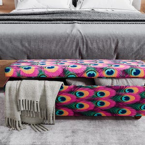 A colorful storage bench with a patterned design sits on a gray carpeted floor in front of a bed.