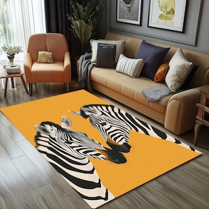 May include: A yellow and orange area rug with a black and white zebra print. The rug features two zebras facing each other with their heads touching.