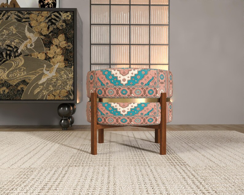 a colorful, patterned chair with a wooden frame, placed on a beige rug in a room with a large window and a decorative cabinet.