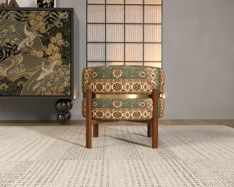 a chair with a green and gold patterned cushion, placed on a white rug in a room with a large window and a decorative cabinet.