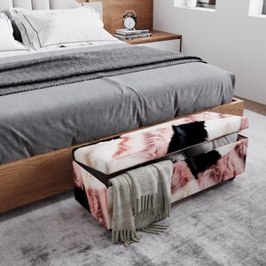 May include: A bedroom scene featuring a bed with gray bedding and a patterned storage bench at the foot. The bench has a lid that is open, revealing storage space. A gray blanket and pillows are visible.