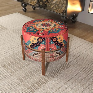 a round, colorful ottoman with a patterned design, placed on a beige rug in a room with a wooden floor.