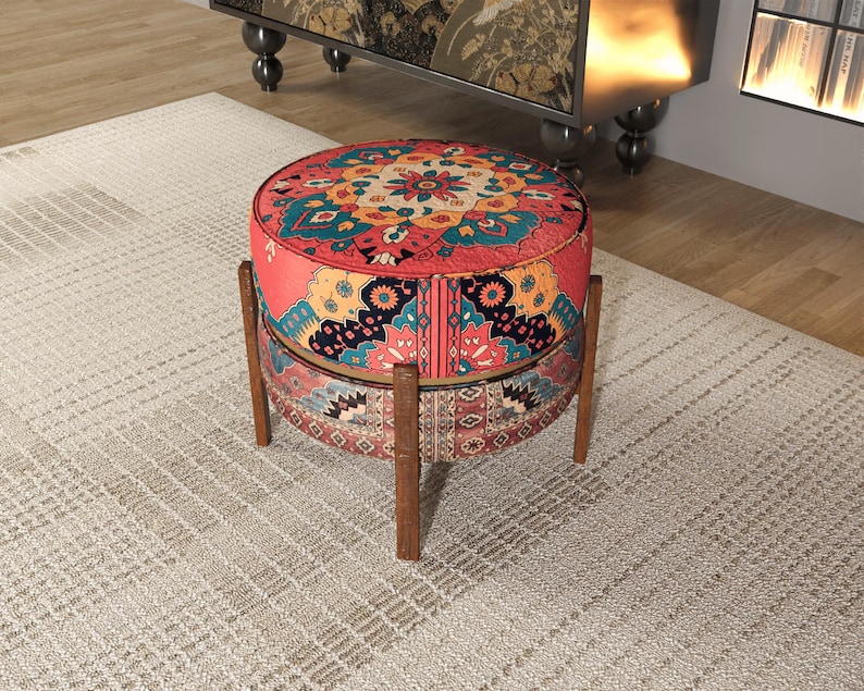 a round, colorful ottoman with a patterned design, placed on a beige rug in a room with a wooden floor.