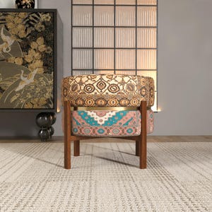 a colorful, patterned chair with a wooden frame, placed on a rug in a room with a large window and a decorative cabinet.