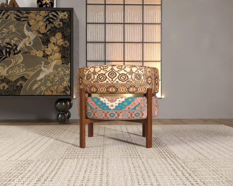 a colorful, patterned chair with a wooden frame, placed on a rug in a room with a large window and a decorative cabinet.