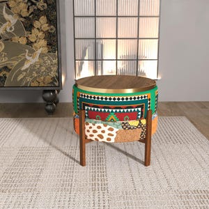 Puede incluir: Un taburete redondo con tapa de madera oscura y borde de metal dorado. La base presenta una tela vibrante y multicolor con patrones geométricos en verde, rojo y blanco, sobre una sección inferior con un estampado de animales en naranja y blanco.