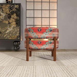a vibrant, patterned chair with a wooden frame, placed on a white rug in a room with a large window and a decorative cabinet.