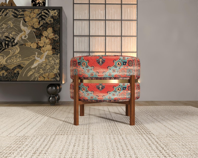 a vibrant, patterned chair with a wooden frame, placed on a white rug in a room with a large window and a decorative cabinet.