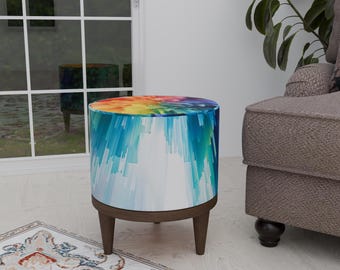 May include: A colorful round ottoman with a white base and wooden legs. The ottoman has a blue, green, yellow, and orange abstract design.