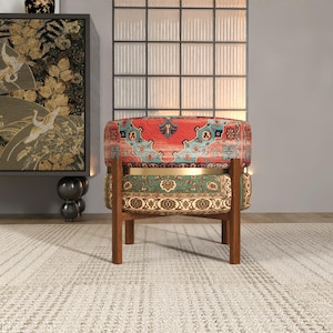 a vibrant, multi-colored chair with a patterned seat and backrest, placed on a white rug in a room with a large window and a black and gold cabinet.