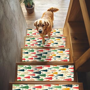 May include: A set of four non-slip stair treads with a colorful Christmas tree pattern. The treads are beige with red, green, blue, yellow, and orange trees. A golden retriever dog is standing on the stairs.