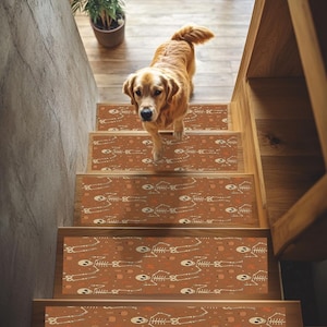May include: A golden retriever walks down a wooden staircase adorned with decorative stair treads. The treads feature a repeating pattern of white skeletons and orange pumpkins on a brown background, creating a Halloween theme.