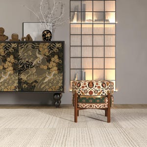 a modern living room with a black and gold cabinet, a patterned ottoman, and a glass-paneled divider.