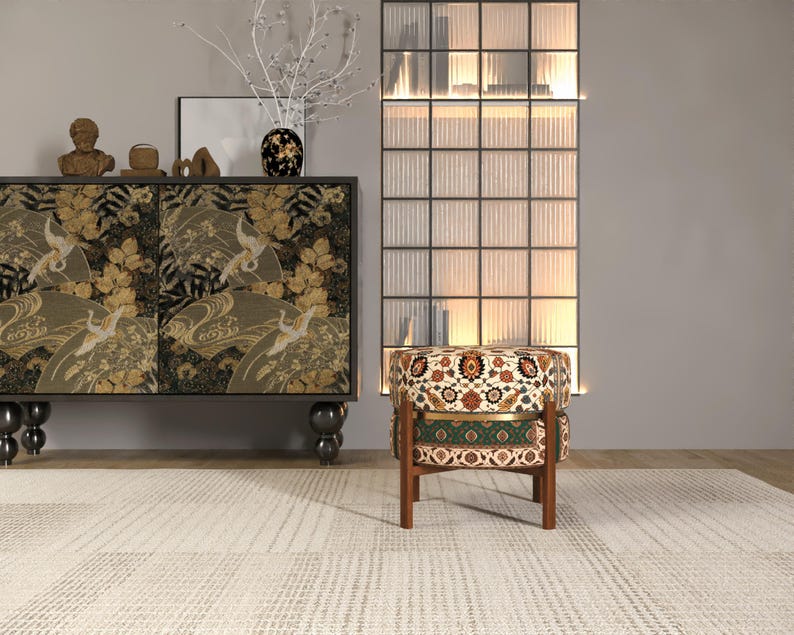 a modern living room with a black and gold cabinet, a patterned ottoman, and a glass-paneled divider.