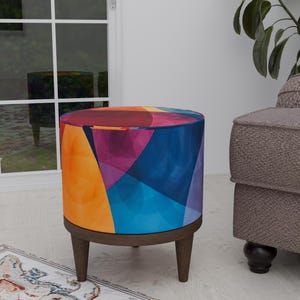 May include: A colorful round ottoman with a geometric pattern in shades of orange, blue, purple, and red. The ottoman has four wooden legs.
