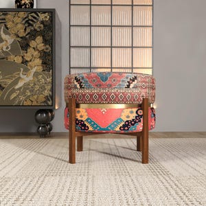 a vibrant, patterned chair with a wooden frame, placed in a room with a rug and a large window.