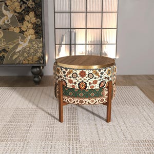 a modern, round table with a wooden top and a colorful, patterned seat. The table is placed on a white rug, and there is a large window in the background.