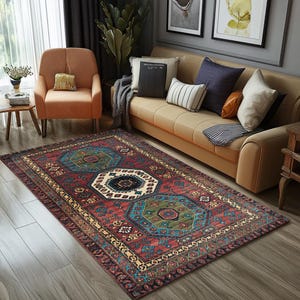 May include: A rectangular rug with a traditional design. The rug has a red background with geometric patterns in teal, green, black, and white. It is placed on a wooden floor in a living room setting.