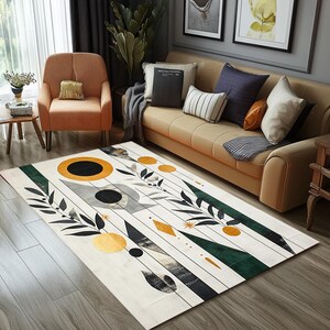 Könnte beinhalten: Abstrakter Teppich mit weißem Hintergrund, schwarzen und grauen geometrischen Formen, grünen Blättern und goldenen Akzenten. Der Teppich liegt auf einem Holzboden.