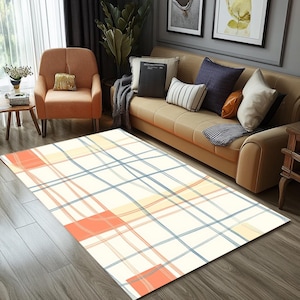 Könnte beinhalten: Ein weißer Teppich mit einem karierten Muster in Orange-, Gelb- und Blautönen. Der Teppich liegt auf einem Holzboden in einem Wohnzimmer.