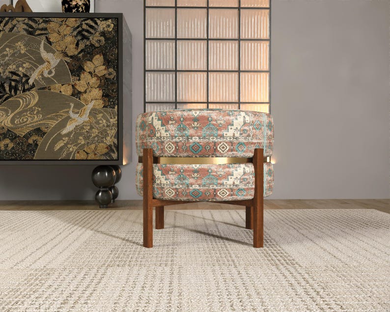 a modern living room with a patterned ottoman, a wooden chair, and a large window with a black and white patterned curtain.